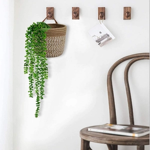 Hanging woven cotton rope plant basket with faux string of pearls greenery on white wall