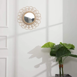 Detail of round sunburst wall mirror with natural woven rattan petals in a minimalist room