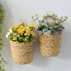 Hanging seagrass woven baskets with yellow daisies and eucalyptus leaves on a white wall