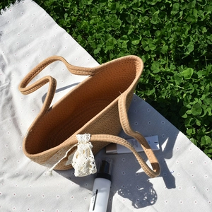 Detail shot of khaki woven straw tote bag with white lace bow on daisy picnic cloth