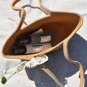 Top view of handmade woven straw tote bag with cream lace bow and skincare storage