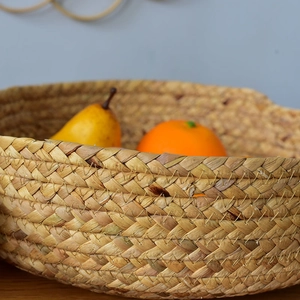 Natural hand-woven straw storage basket used as a round fruit bowl for home organization