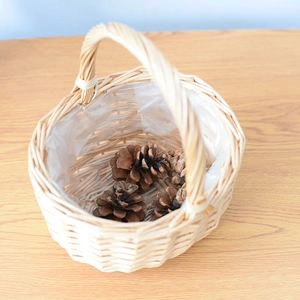 Macro detail of hand-woven wicker basket with clear plastic liner and natural pine cones
