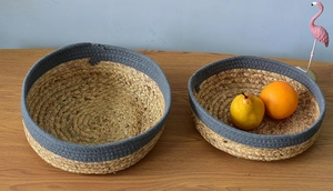 Set of two round hand-woven grass storage baskets with gray contrast trim and rustic finish