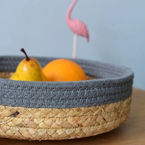 Close-up of a dual-color woven seagrass storage basket filled with fresh fruits