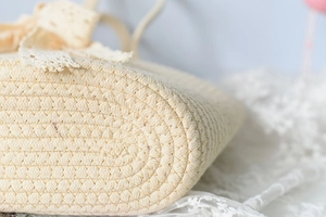 Macro detail of hand-woven cotton rope shoulder bag showing spiral bottom and lace trim