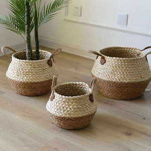 Three-piece woven seagrass storage baskets with two-tone design used as plant pot covers