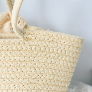 Detailed close-up of handmade woven straw bag featuring a delicate beige lace bow accent