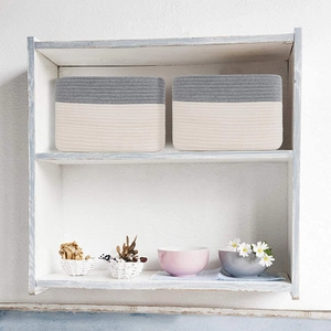 Detail of grey and beige cotton rope storage basket set on a white wooden shelf