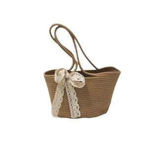 Handwoven straw tote bag with white lace bow detail and slim handles for summer beach use
