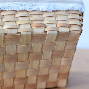Close-up of handwoven wood storage basket with white lace trim and linen lining details