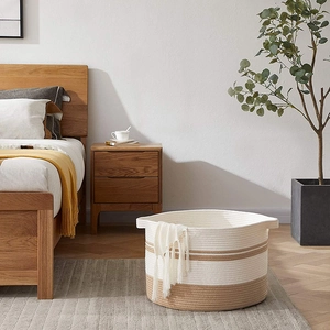 Detail of woven cotton rope laundry basket texture with tassels in a bedroom setting