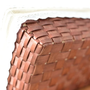 Detailed view of woven storage basket featuring red-brown wood strips and lace fabric lining