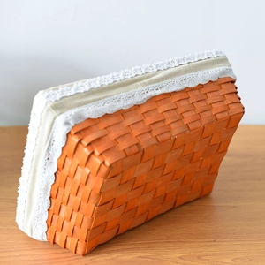 Detail of hand-woven storage basket with orange wood slats and white lace fabric lining