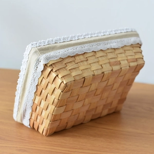 Close-up of handwoven rectangular storage basket with white lace trim and linen lining