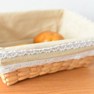 Close-up of hand-woven rectangular basket with cream linen lining and white lace trim