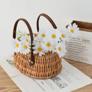 Detail of woven flower basket with brown leather handles and white daisy floral decor