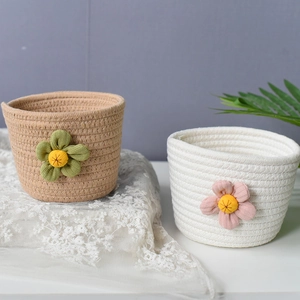 Detail view of woven cotton rope storage baskets with delicate plush flower decorations