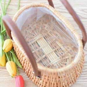 Detail view of woven flower basket with waterproof lining and brown leather handles