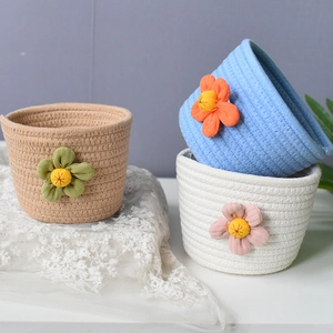 Detail view of woven cotton rope storage baskets with decorative fabric floral accents