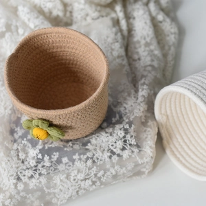Detail of hand-woven cotton rope storage basket with decorative flower on lace background