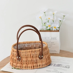 Handwoven wicker storage basket with leather handles and waterproof lining on wooden table