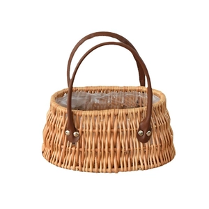 Handwoven oval wicker basket with leather handles and plastic liner for floral arrangements
