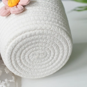 Detail of white cotton rope woven basket with pink fabric flower and thick spiral texture