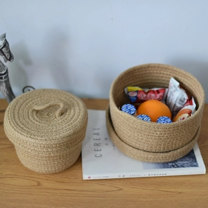 Two-piece set of natural woven jute storage baskets with lid on a wooden desk