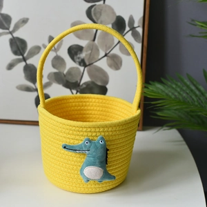 Detail of yellow woven cotton rope basket featuring a cute blue crocodile doll accessory