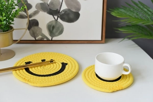 Detailed macro view of yellow woven cotton coasters with black smiley face design