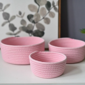 Three-piece set of pink cotton rope woven storage baskets in small, medium, and large sizes