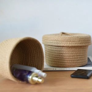 Detail of two handmade woven storage baskets with lid and natural jute texture for desk