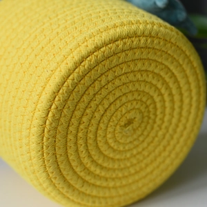 Detailed close-up of spiral woven cotton rope pattern on a bright yellow storage basket