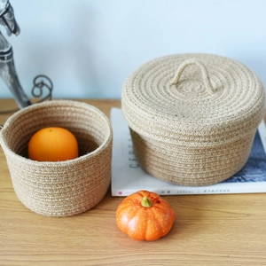 Detail of handwoven jute storage baskets with lids on wooden table for home organization