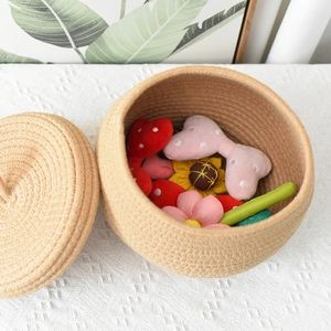 Close-up of cotton rope pumpkin storage basket filled with plush accessories and lid