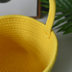 Detailed close-up of yellow woven cotton rope basket showing sturdy handle attachment