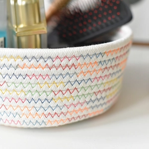 Close-up of white woven cotton storage basket featuring colorful zigzag embroidery detail