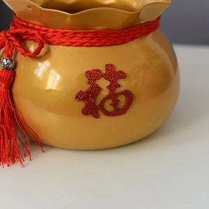 Detail eines goldenen Glücksbeutel-Blumeneimers mit rotem Fu-Zeichen und Quaste