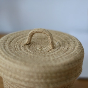 Close-up of handmade jute woven storage basket lid with a sturdy circular handle