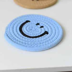 Light blue woven cotton coaster featuring a minimalist black smiley face pattern