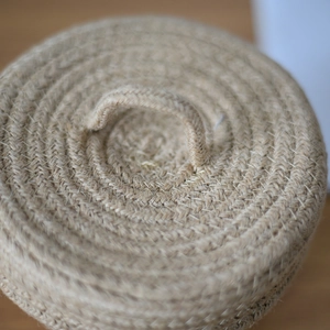 Macro shot of jute woven storage basket lid showing spiral texture and small handle loop
