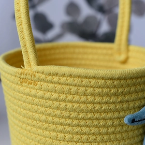 Detailed close-up showing yellow cotton rope weave texture and blue plush handle trim