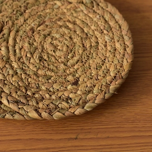 Close-up of hand-woven natural straw heat-resistant round mat with spiral texture