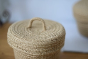 Detailed close-up of handmade jute storage basket lid with handle and woven texture