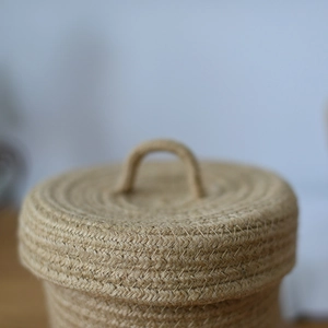 Detailed close-up of a woven cotton and jute storage basket with a lid and handle