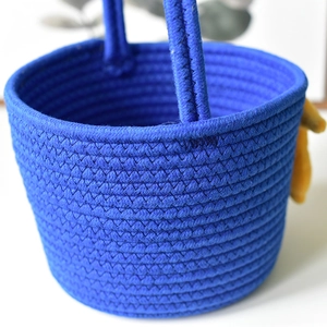 Detail of deep blue woven cotton rope storage basket with sturdy circular handles and charm
