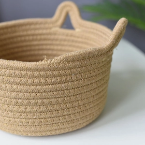 Close-up of handwoven cotton rope storage basket with sturdy triangular handles and fine texture