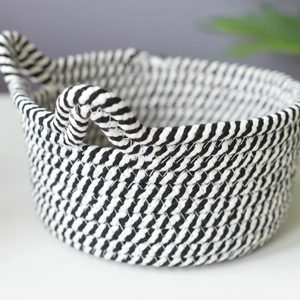 Detail of handwoven black and white striped cotton rope storage basket with ring handles