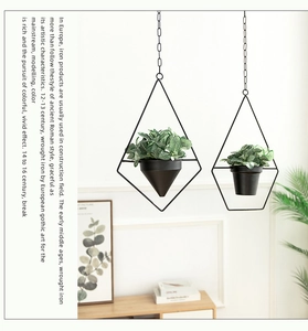 Detail of minimalist black geometric hanging metal planters with faux greenery decor